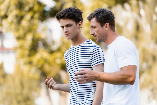 Father and teenage son having a conversation outdoors